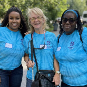 Three women dressed in blue shirts hold signs, showcasing their solidarity and commitment to a common issue.