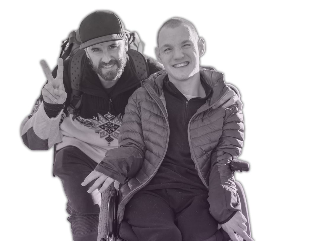 a man and a boy in a wheel chair standing next to each other.