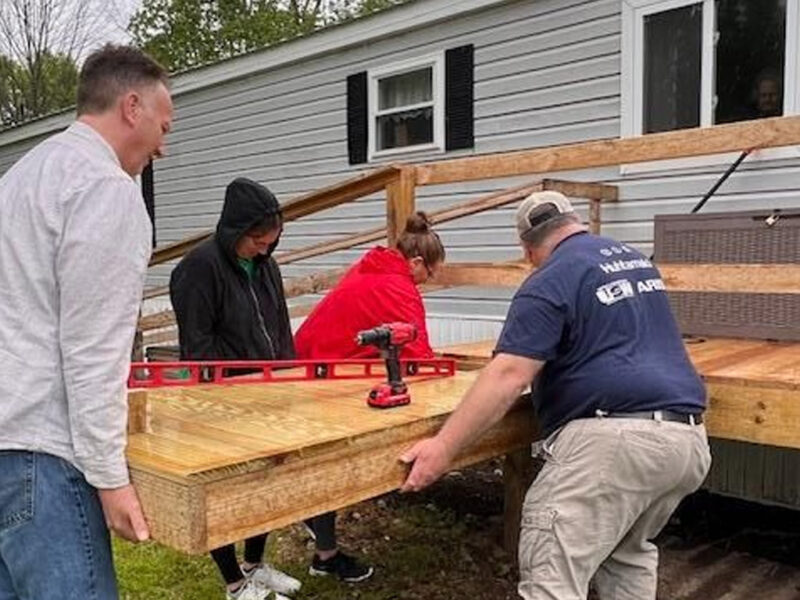 a team of people lifting a wooden ramp